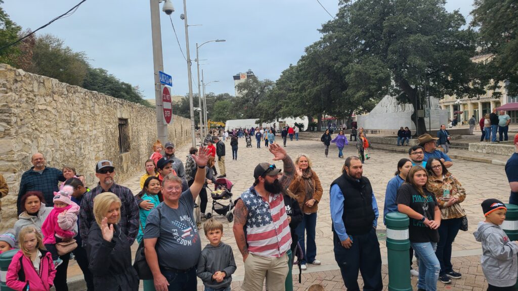 Group of people near the Alamo waving